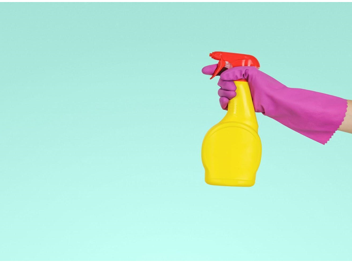 Hand wearing pink glove spraying laminate flooring cleaner